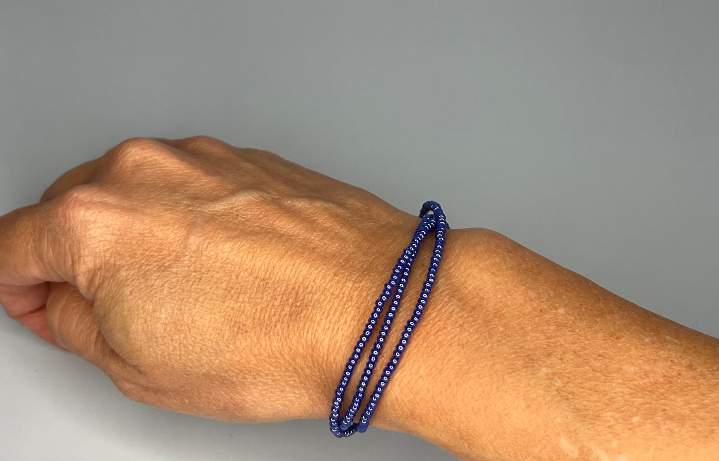 a man's hand wearing a blue beaded bracelet