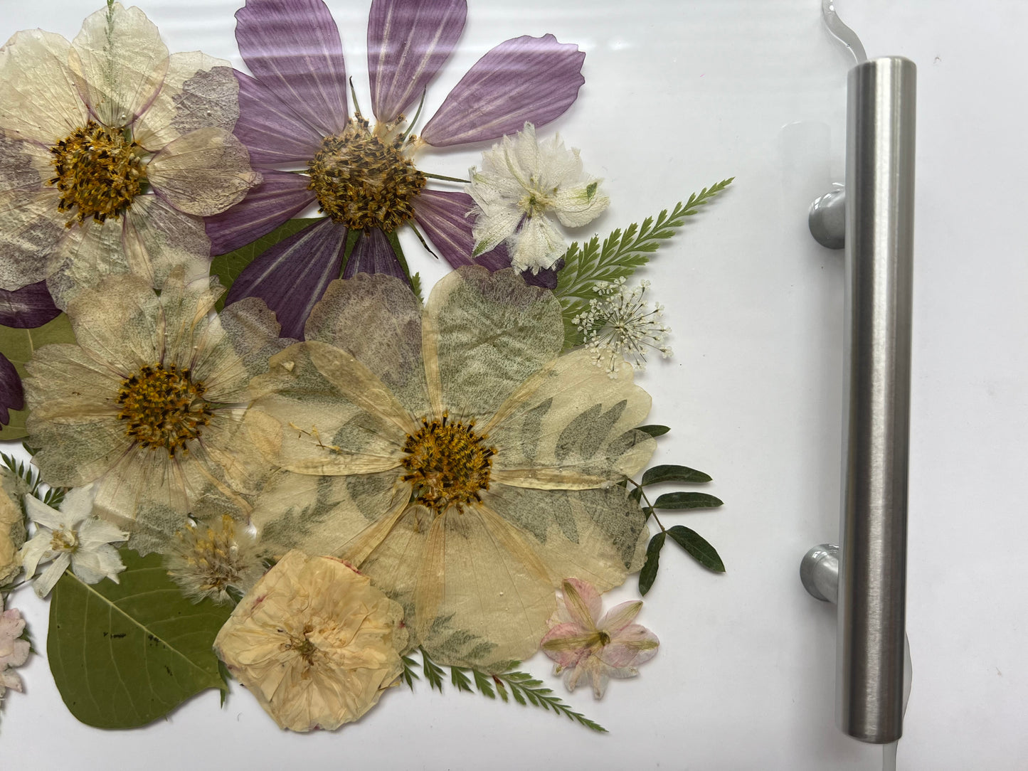 a close-up view of a collection of dried flowers and leaves, arranged on a white surface.