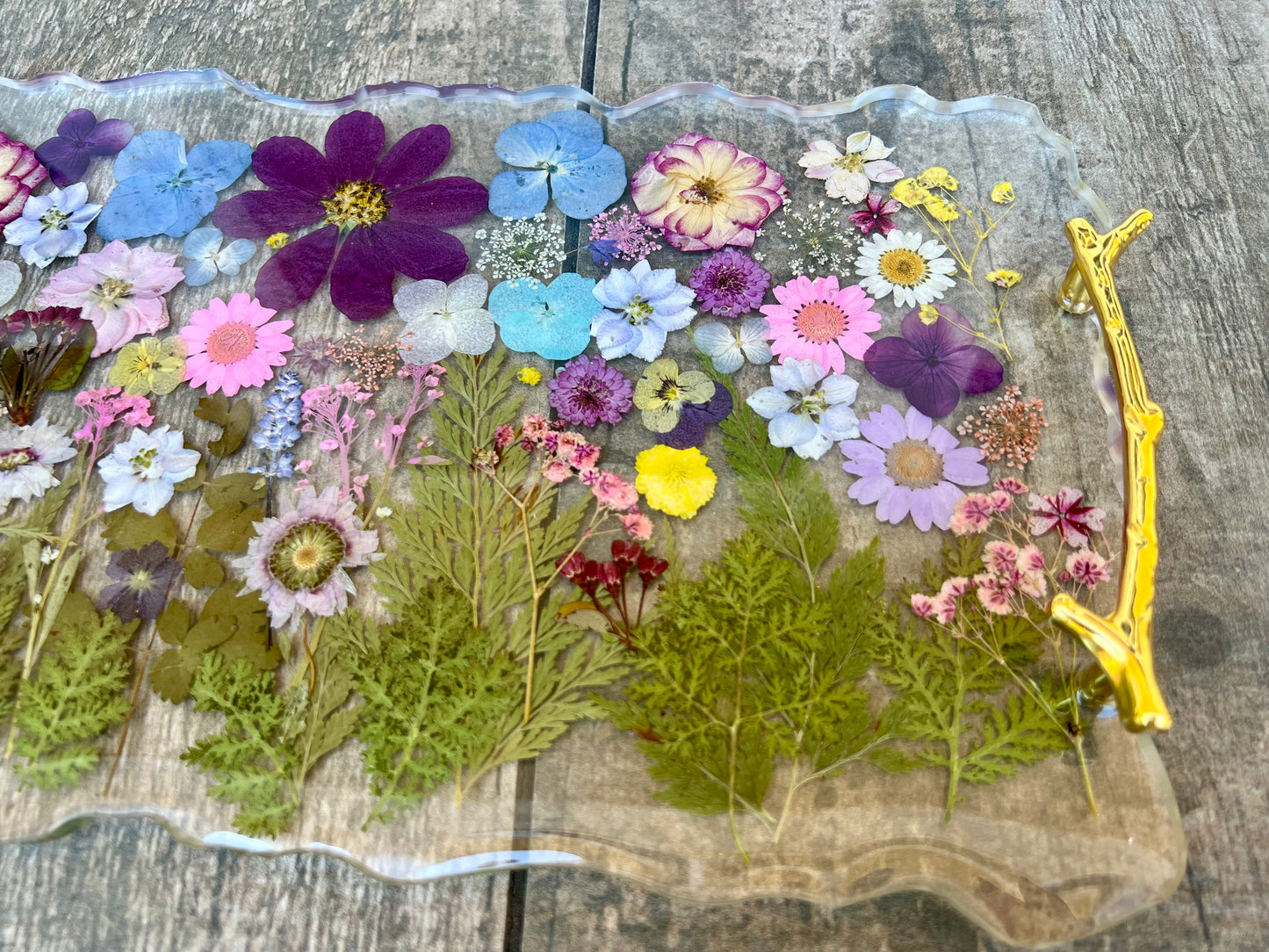 a clear glass tray with a variety of colorful flowers and leaves pressed onto it, creating a visually appealing and natural display.