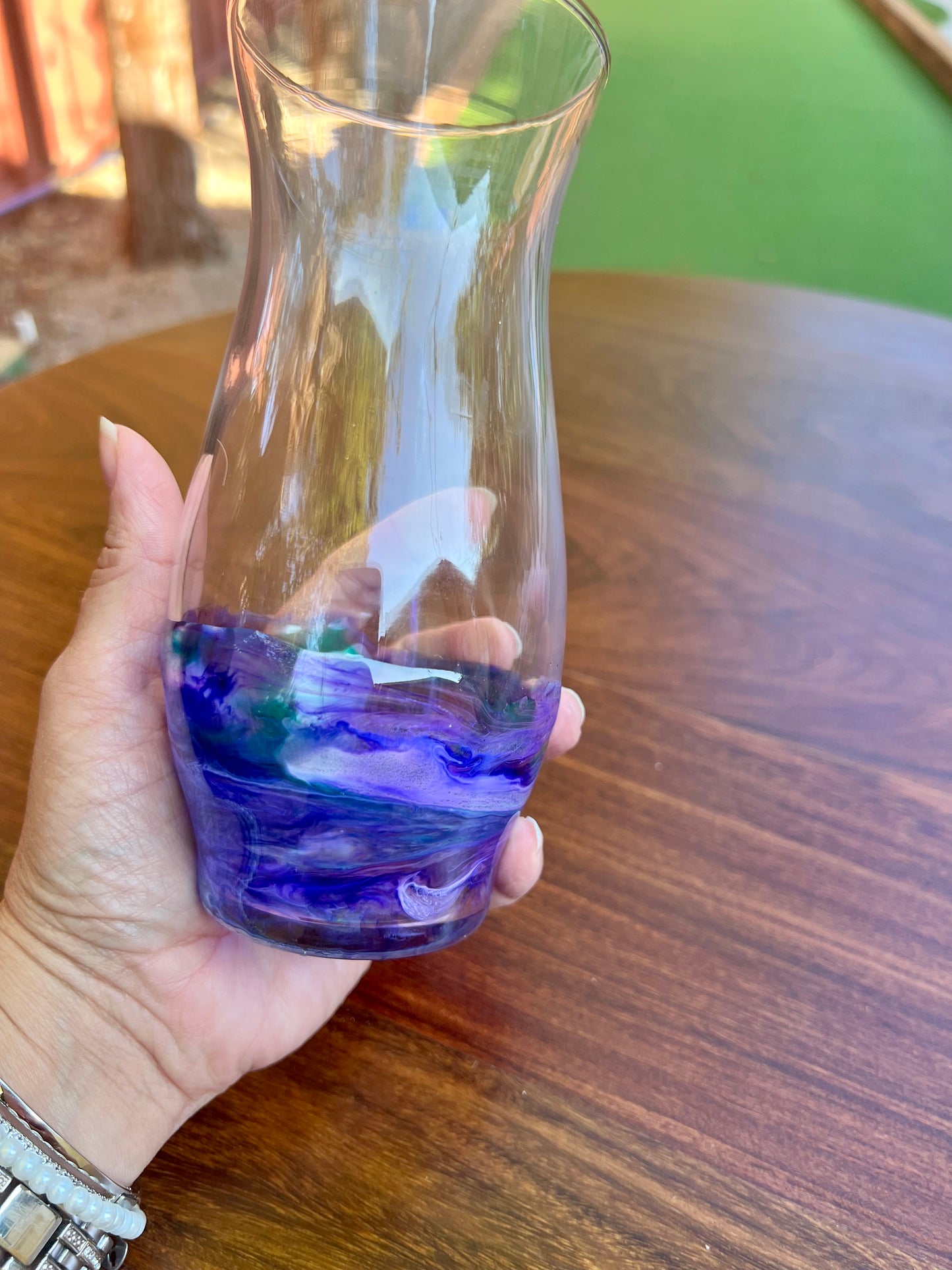 a hand holding a glass with blue and purple liquid in it