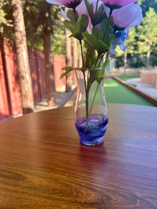 a vase filled with purple flowers on top of a wooden table