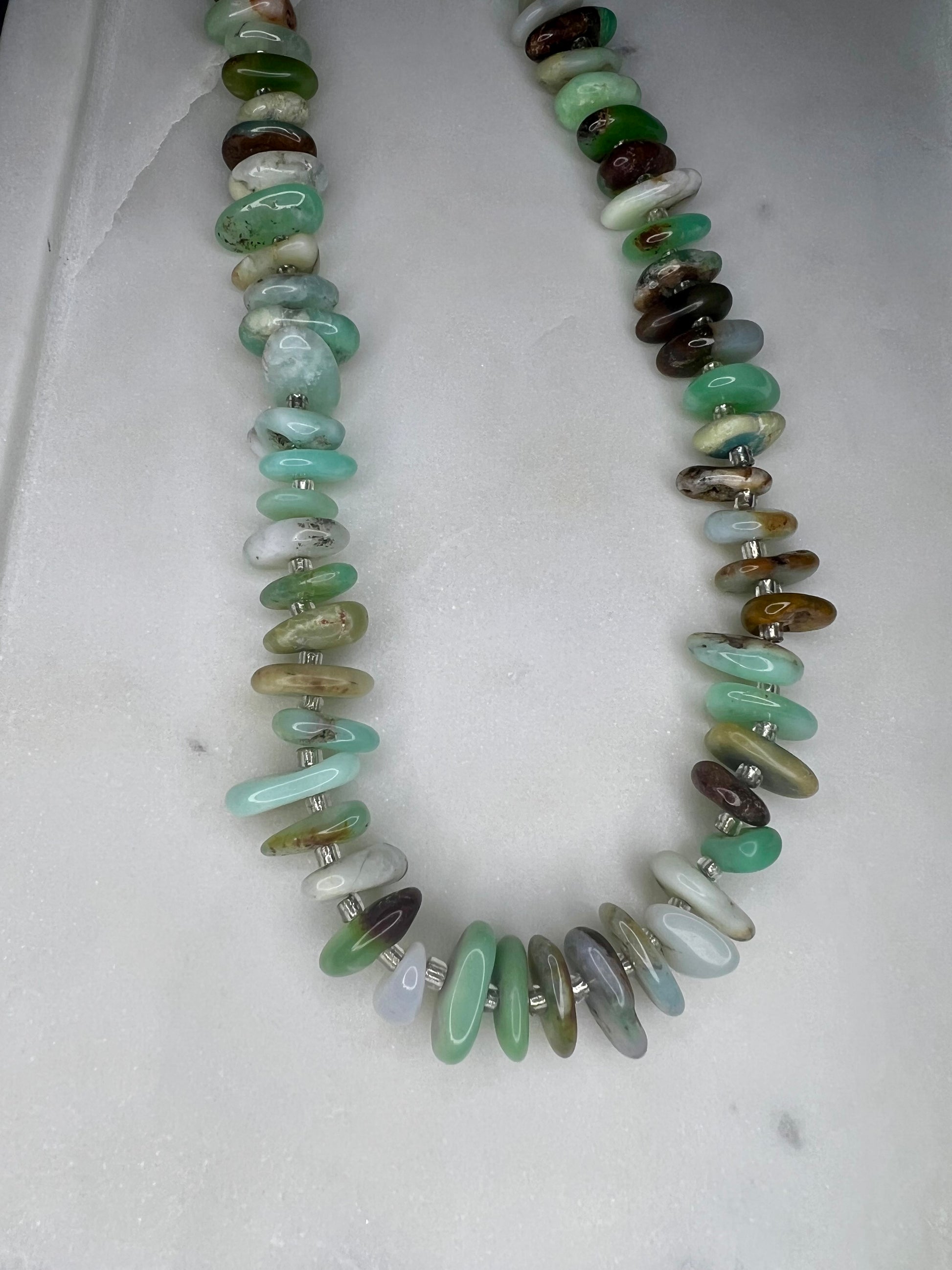 A necklace made of various colored beads, including green, white, and brown, arranged in a row.