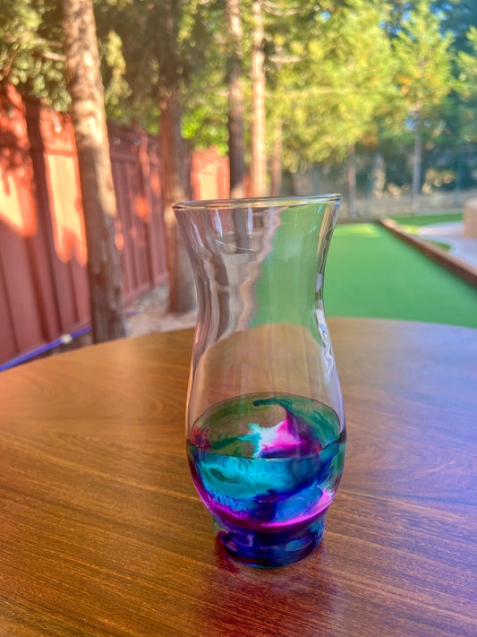 a glass of liquid sitting on top of a wooden table