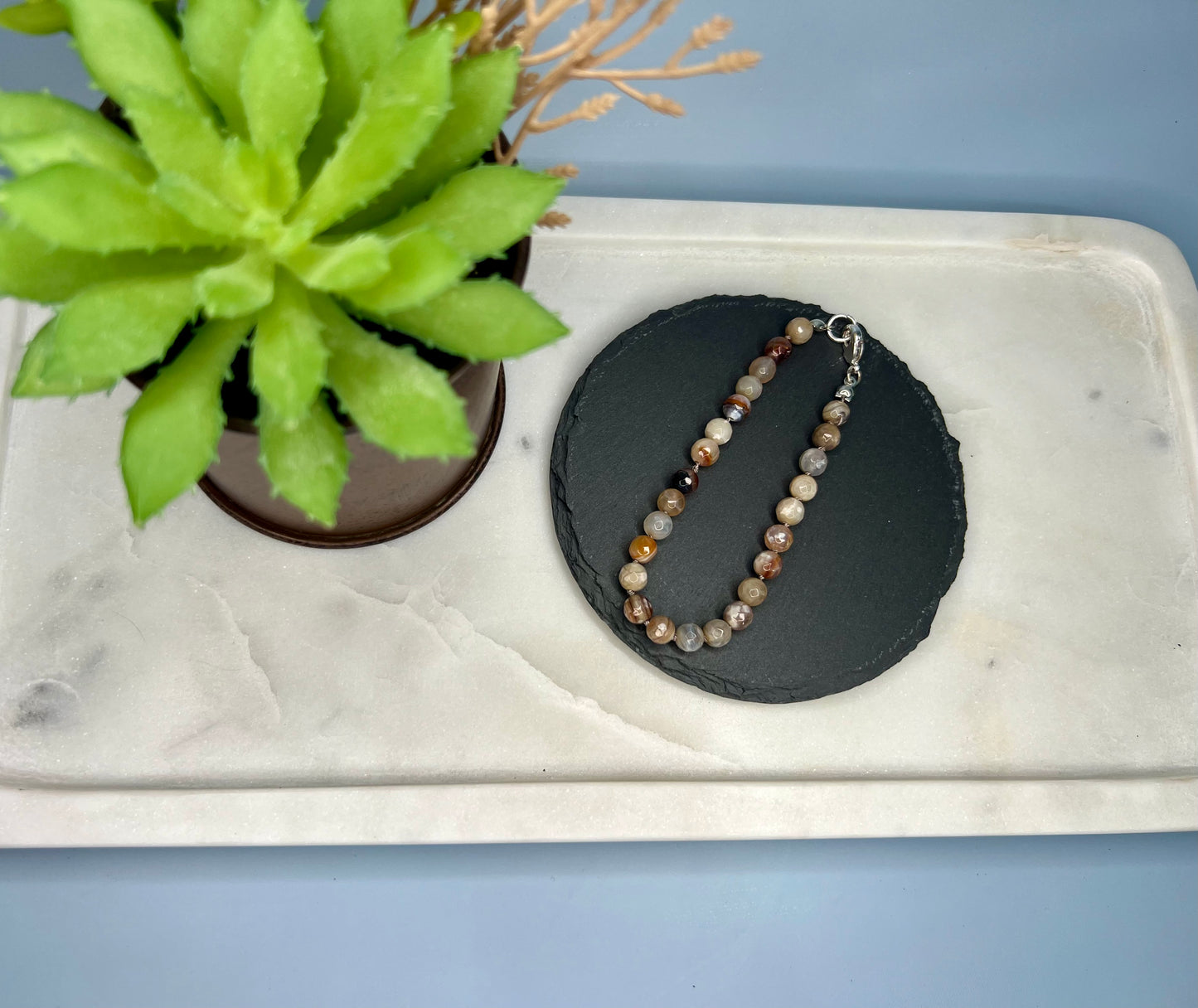 a white tray holding a necklace and a potted plant