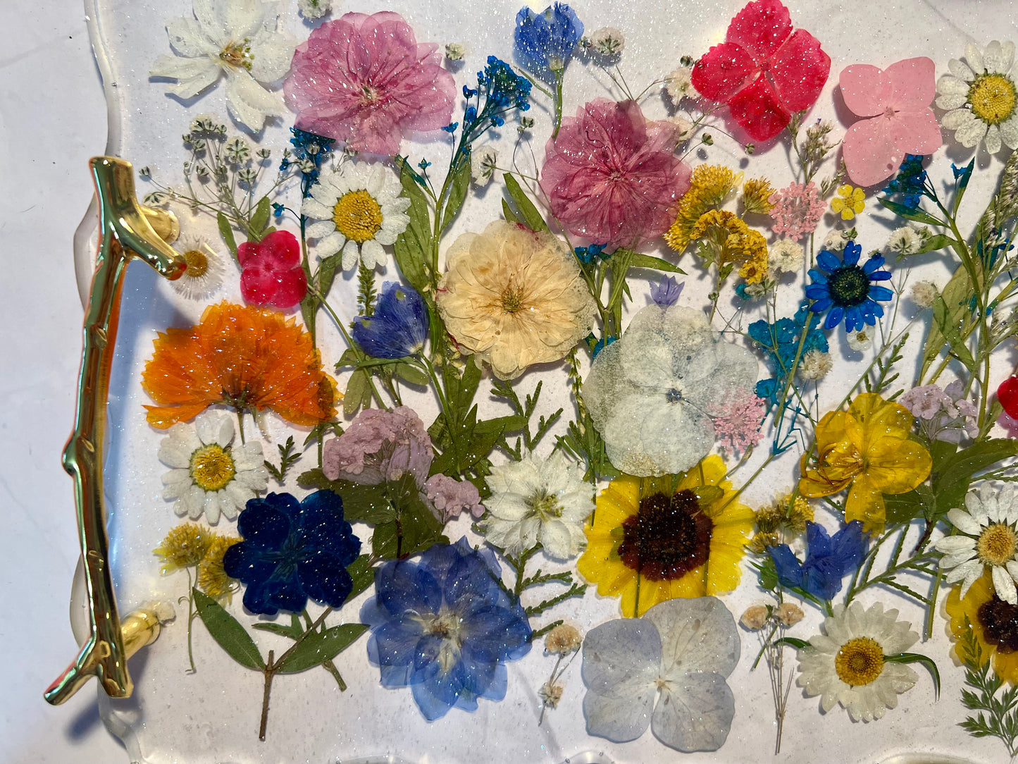 The image is a vibrant display of various colorful flowers, including pink, white, yellow, blue, and purple, arranged in a visually appealing manner.