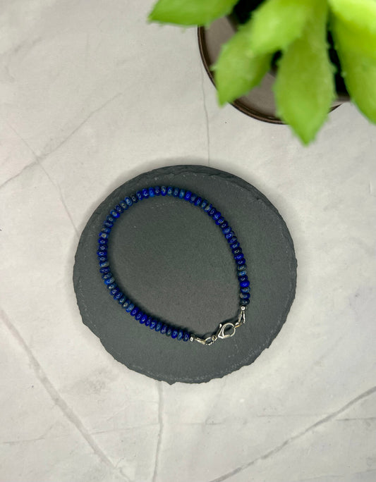 a blue beaded bracelet sitting on top of a table