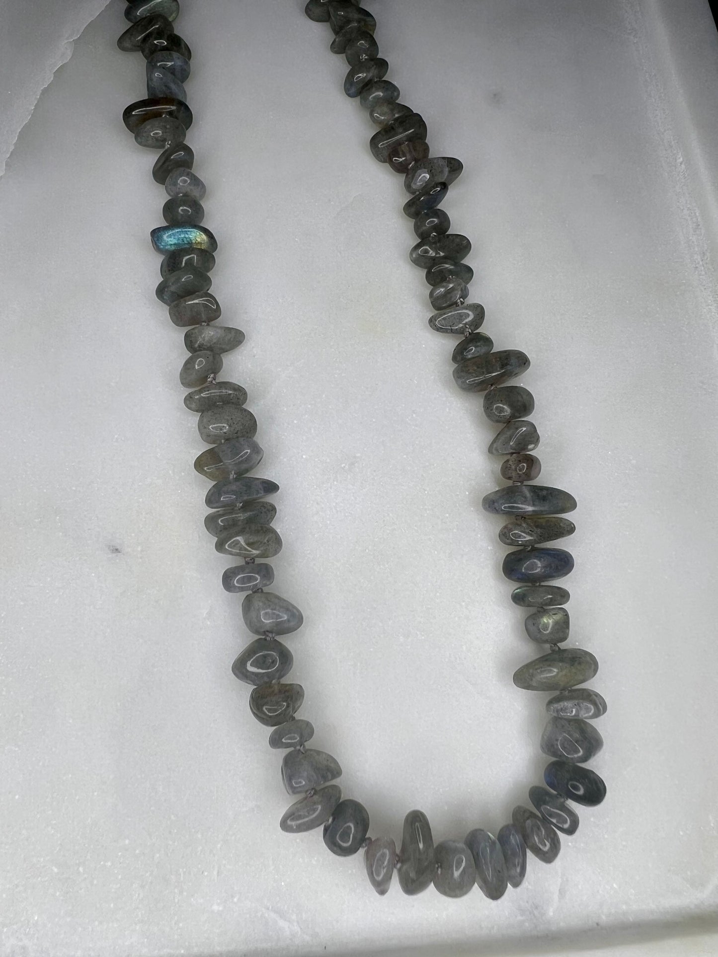 A necklace made of small, irregularly shaped gray stones or beads arranged in a long, continuous strand.