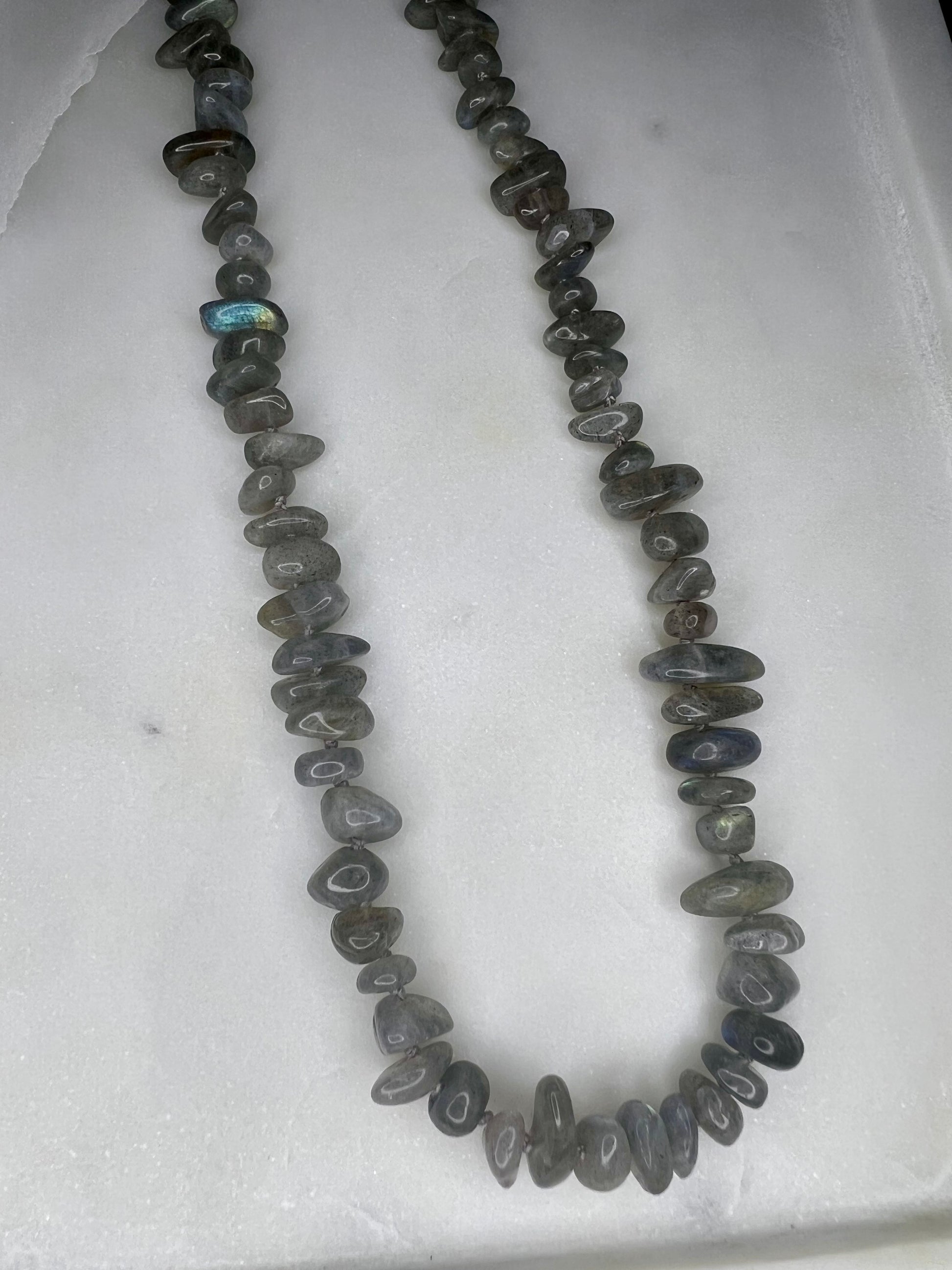 A necklace made of small, irregularly shaped gray stones or beads arranged in a long, continuous strand.