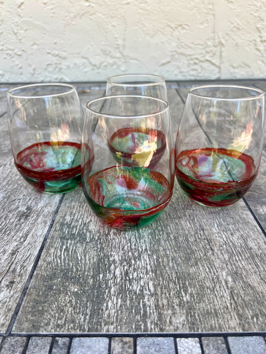 a set of four wine glasses with colorful, swirling patterns in red, green, and white colors, placed on a wooden surface.