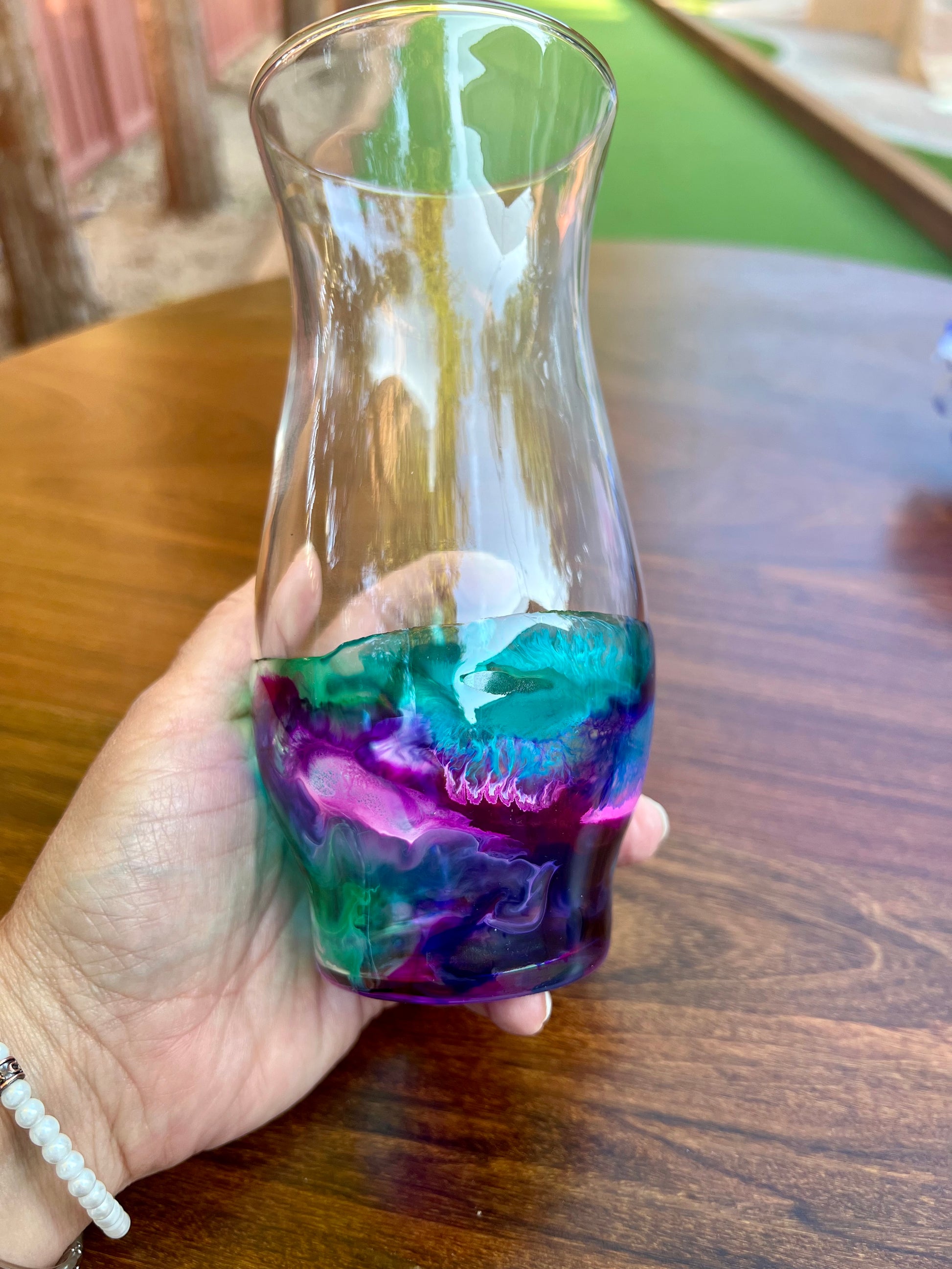 a hand holding a glass with a colorful liquid inside of it