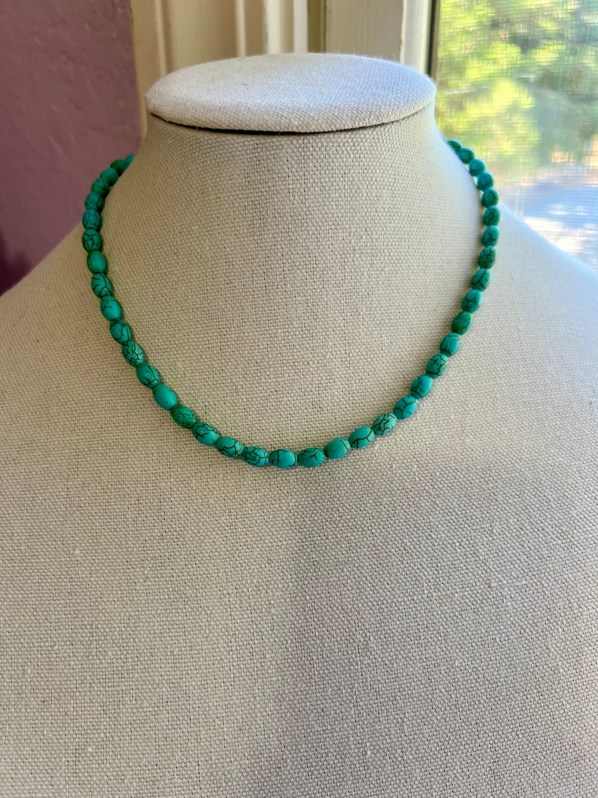 a necklace on a mannequin wearing a white shirt