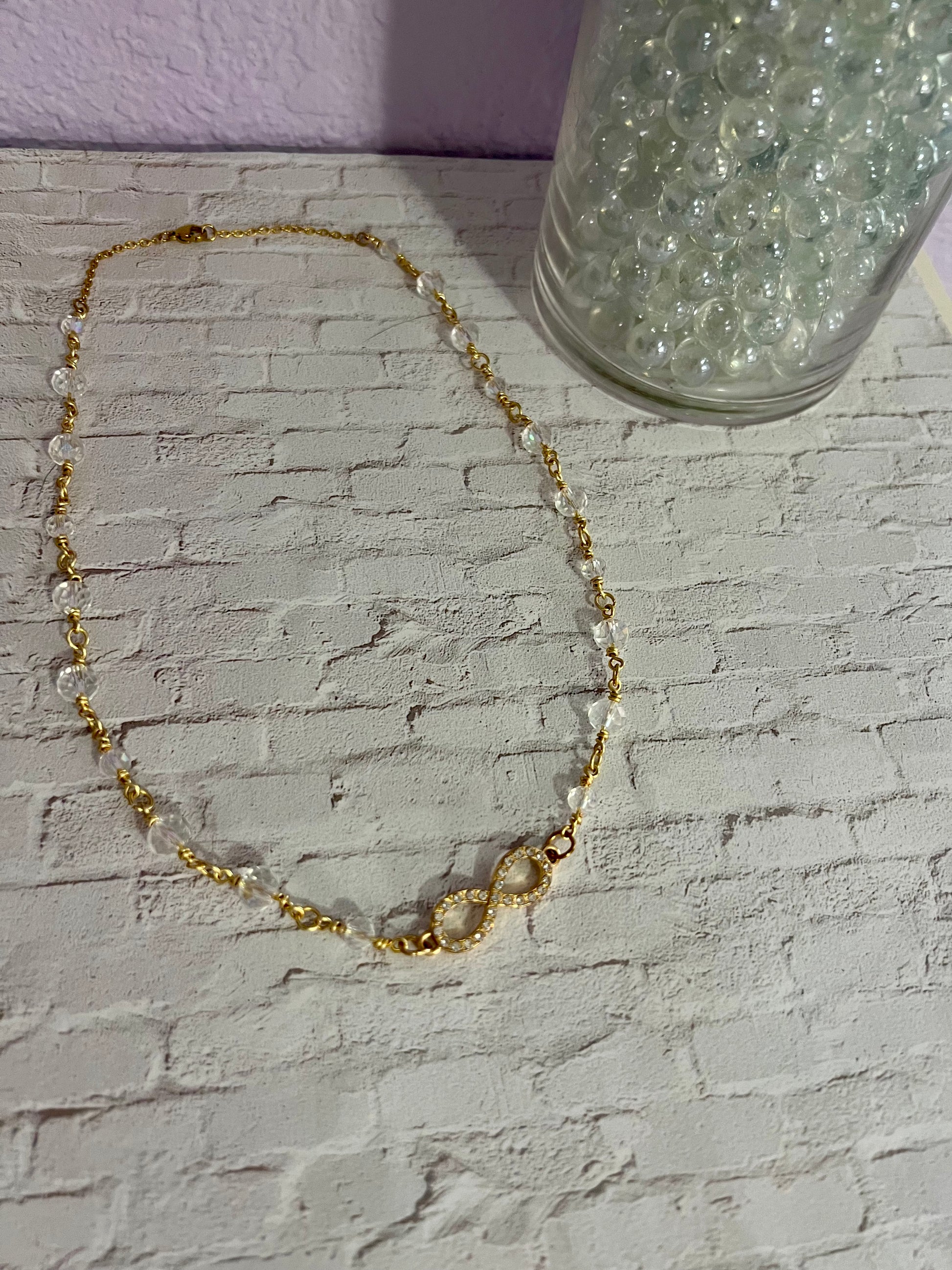 a gold chain bracelet with a glass of water