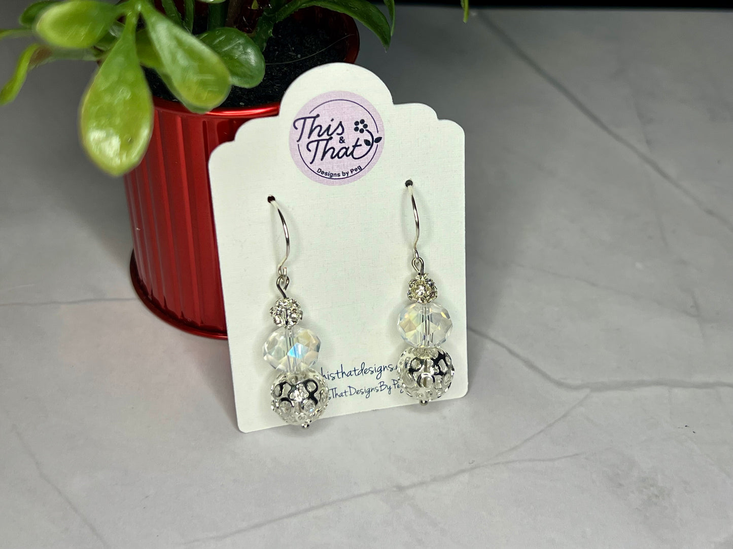 a pair of earrings sitting next to a potted plant