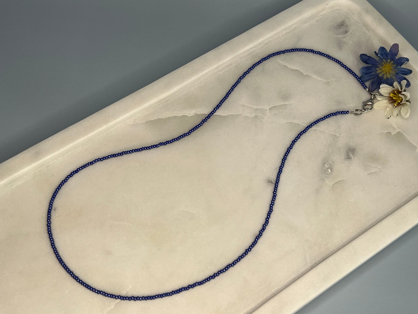 a blue beaded necklace with a flower on it