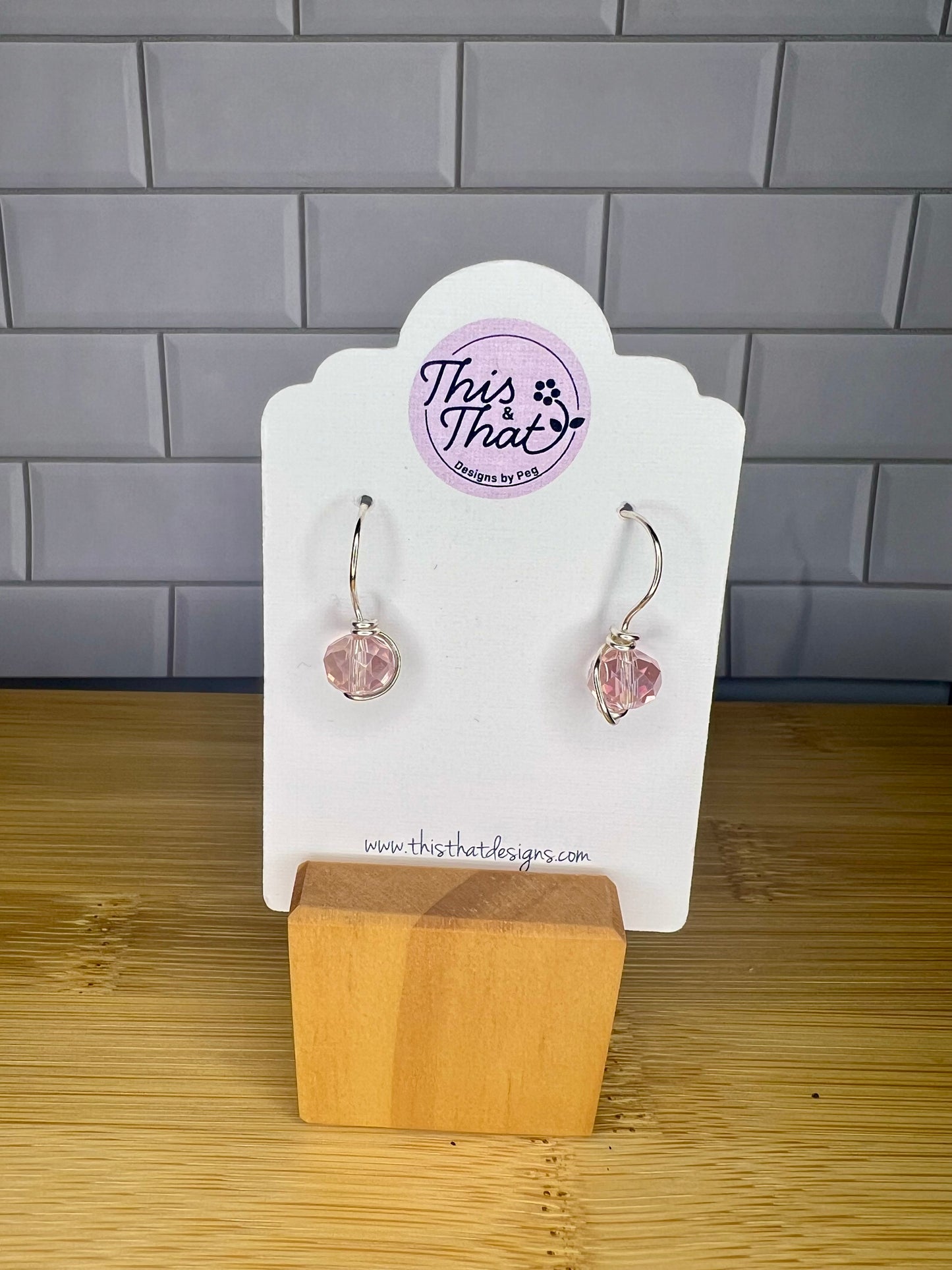 a pair of earrings displayed on a white stand, with a wooden base.