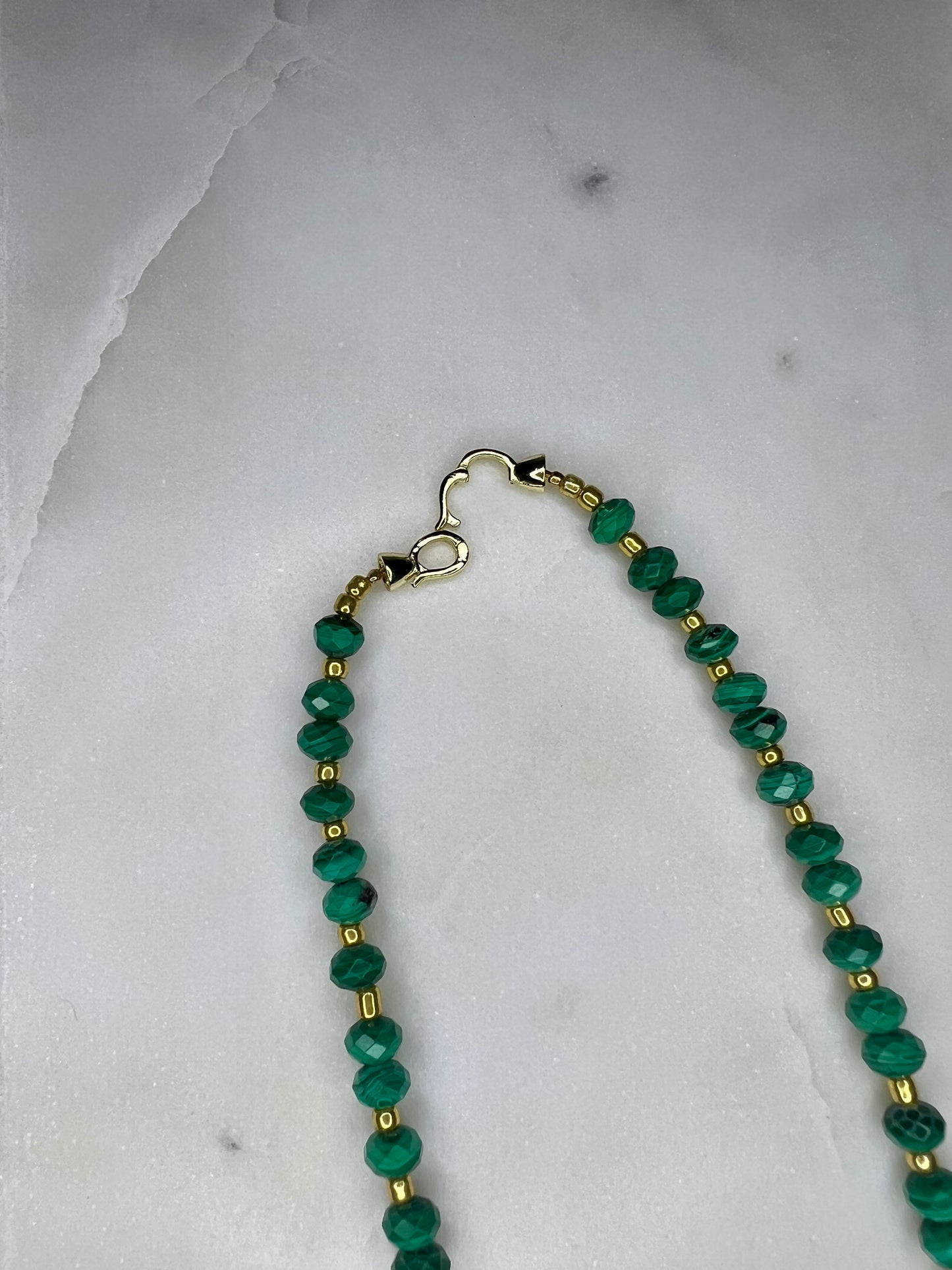 A necklace with green beads and gold-colored clasp.