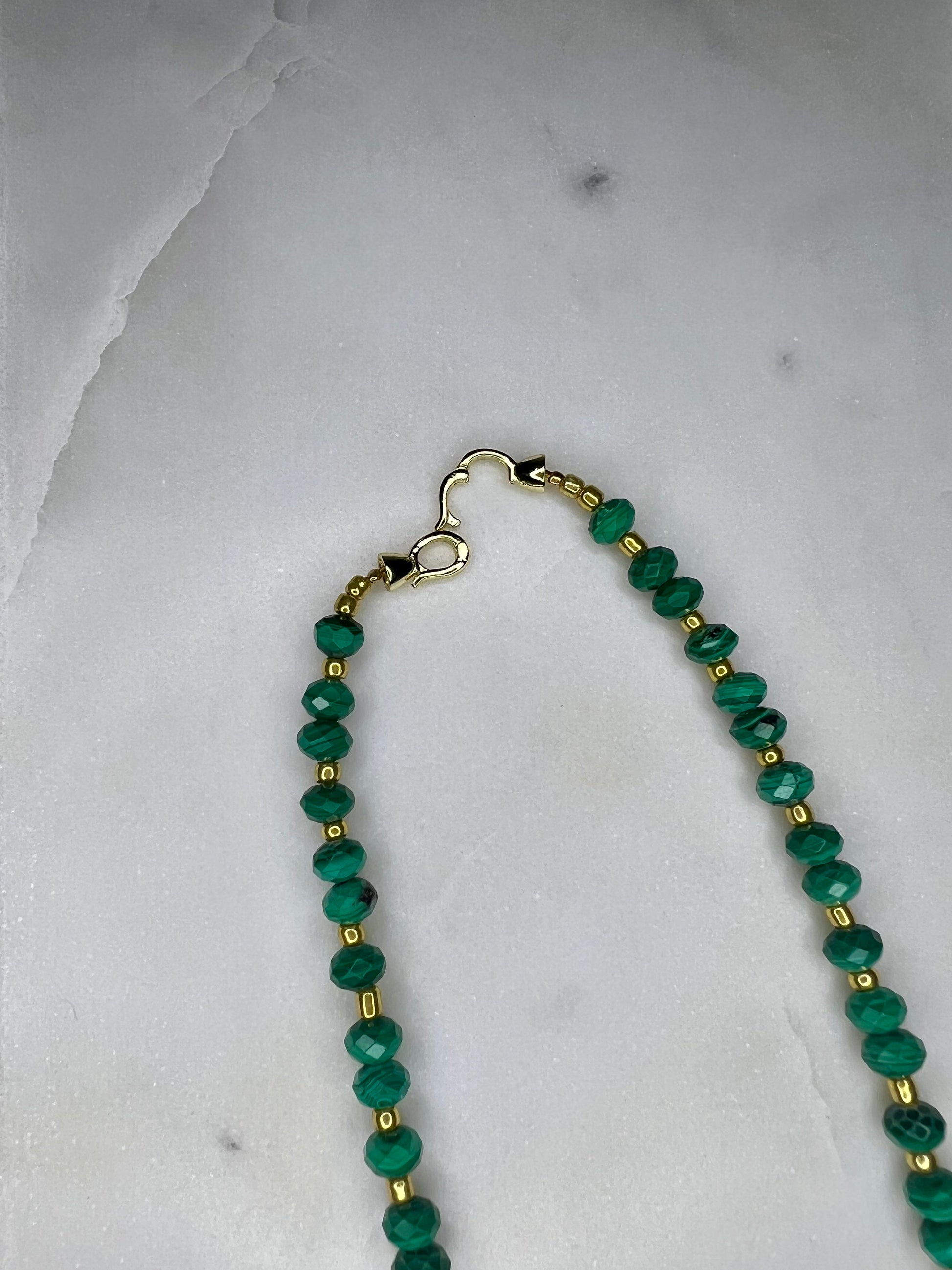 A necklace with green beads and gold-colored clasp.