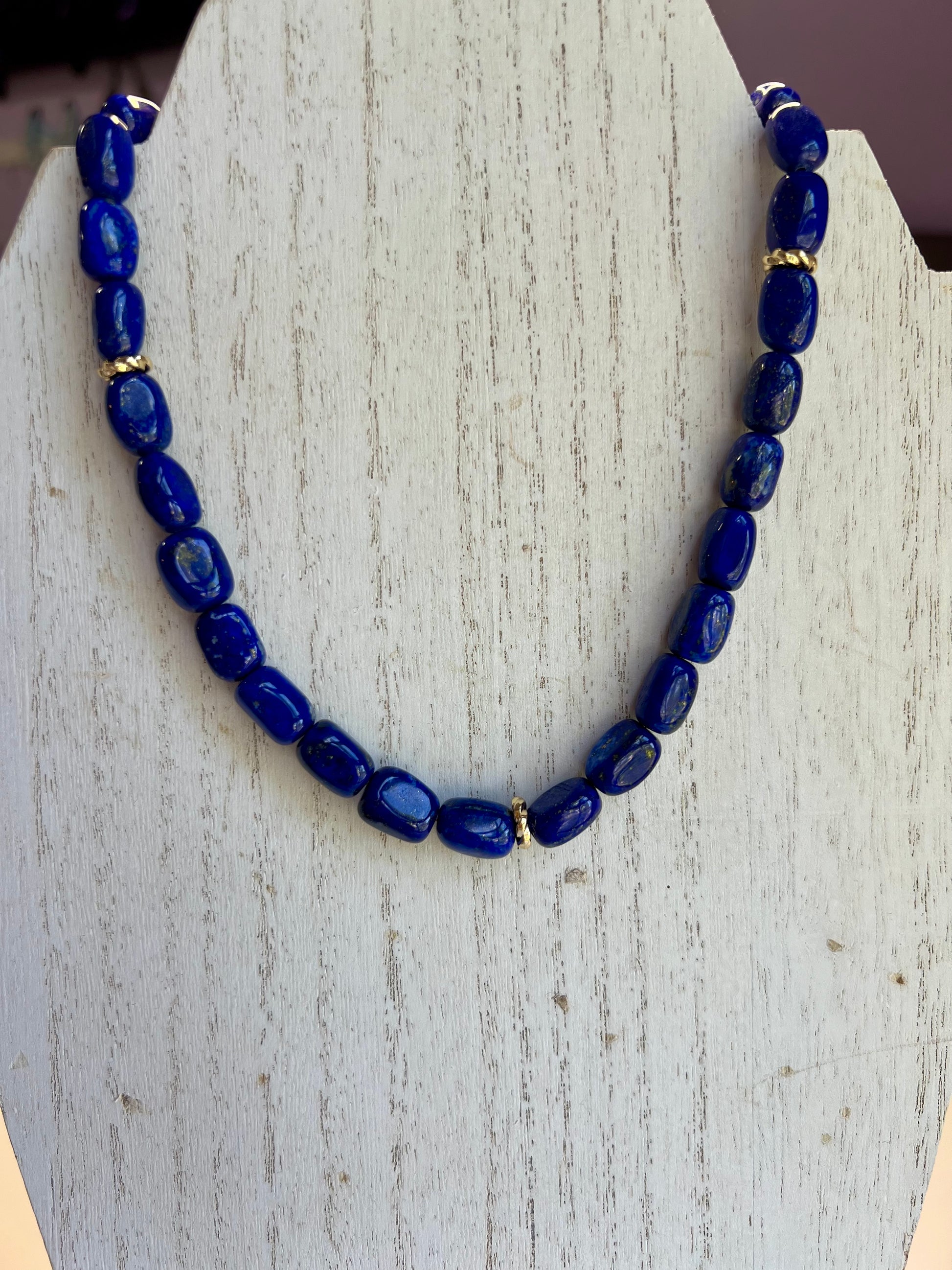 a blue beaded necklace is displayed on a stand