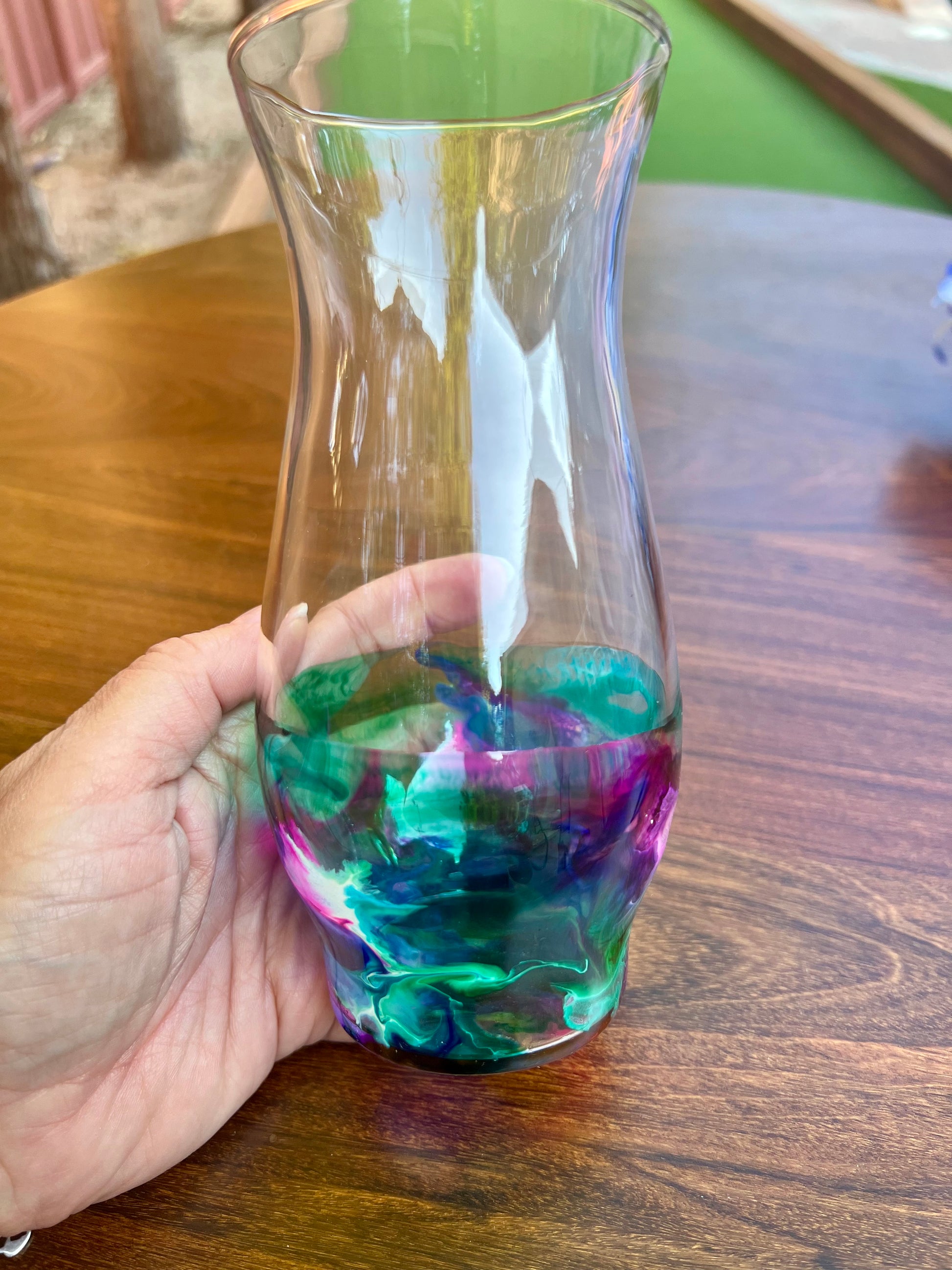 a hand holding a glass with a liquid inside of it