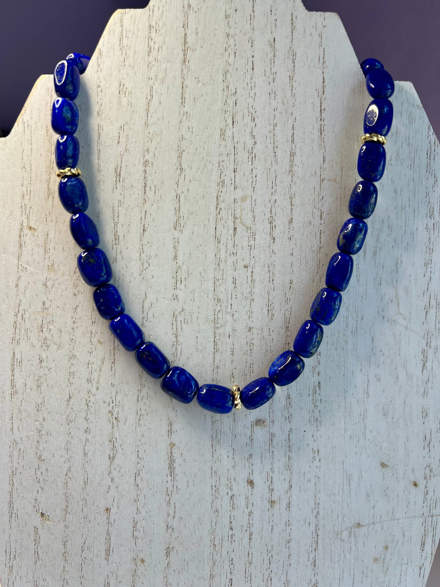 a blue beaded necklace on a wooden stand