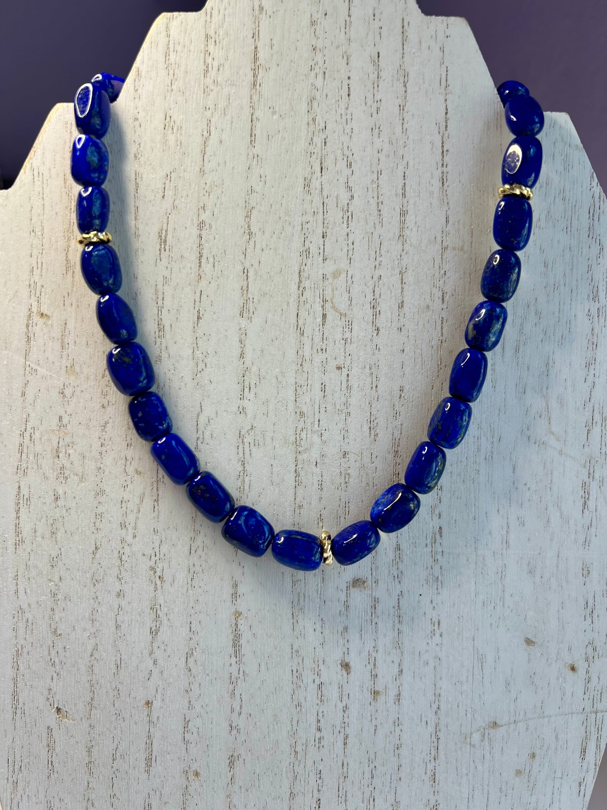 a blue beaded necklace on a wooden stand