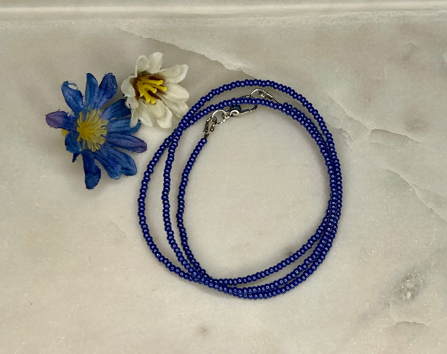 a blue beaded necklace with a flower on it