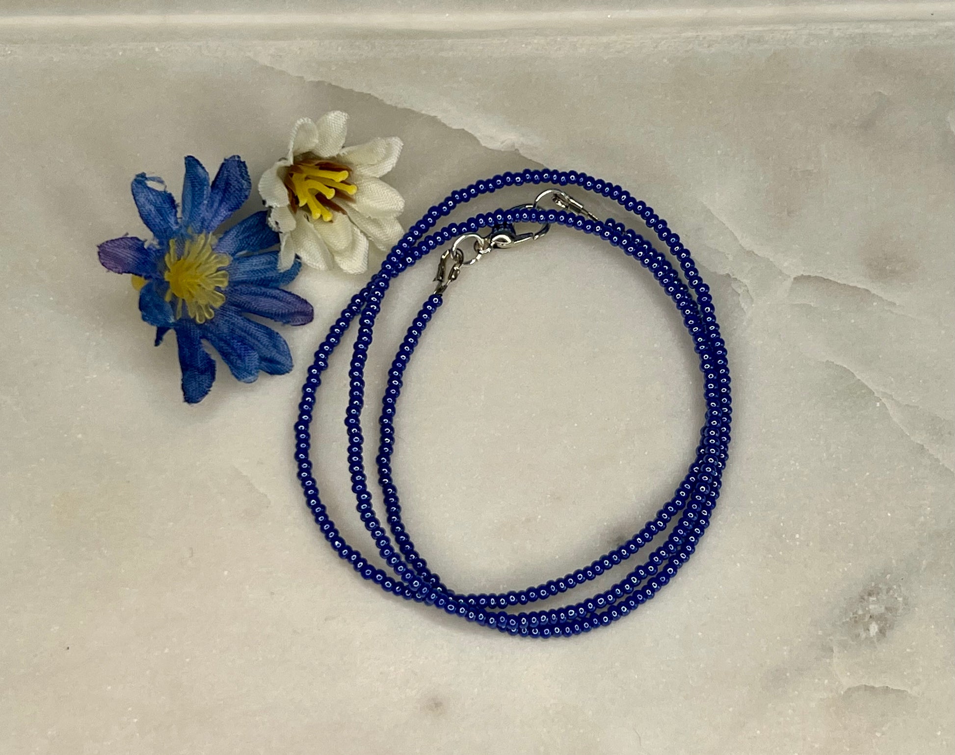 a blue beaded necklace with a flower on it
