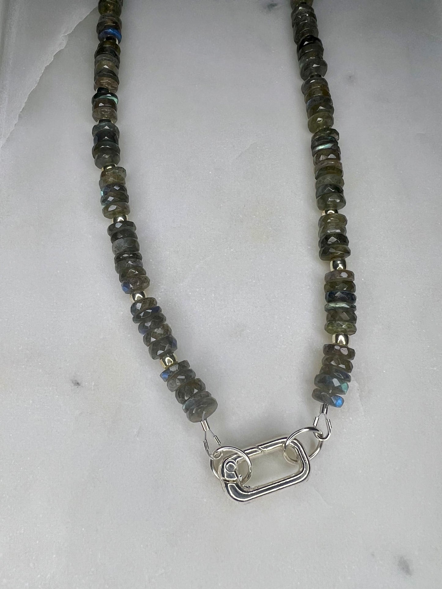 A necklace made of small, dark-colored beads with a silver clasp and a silver-colored metal clasp.