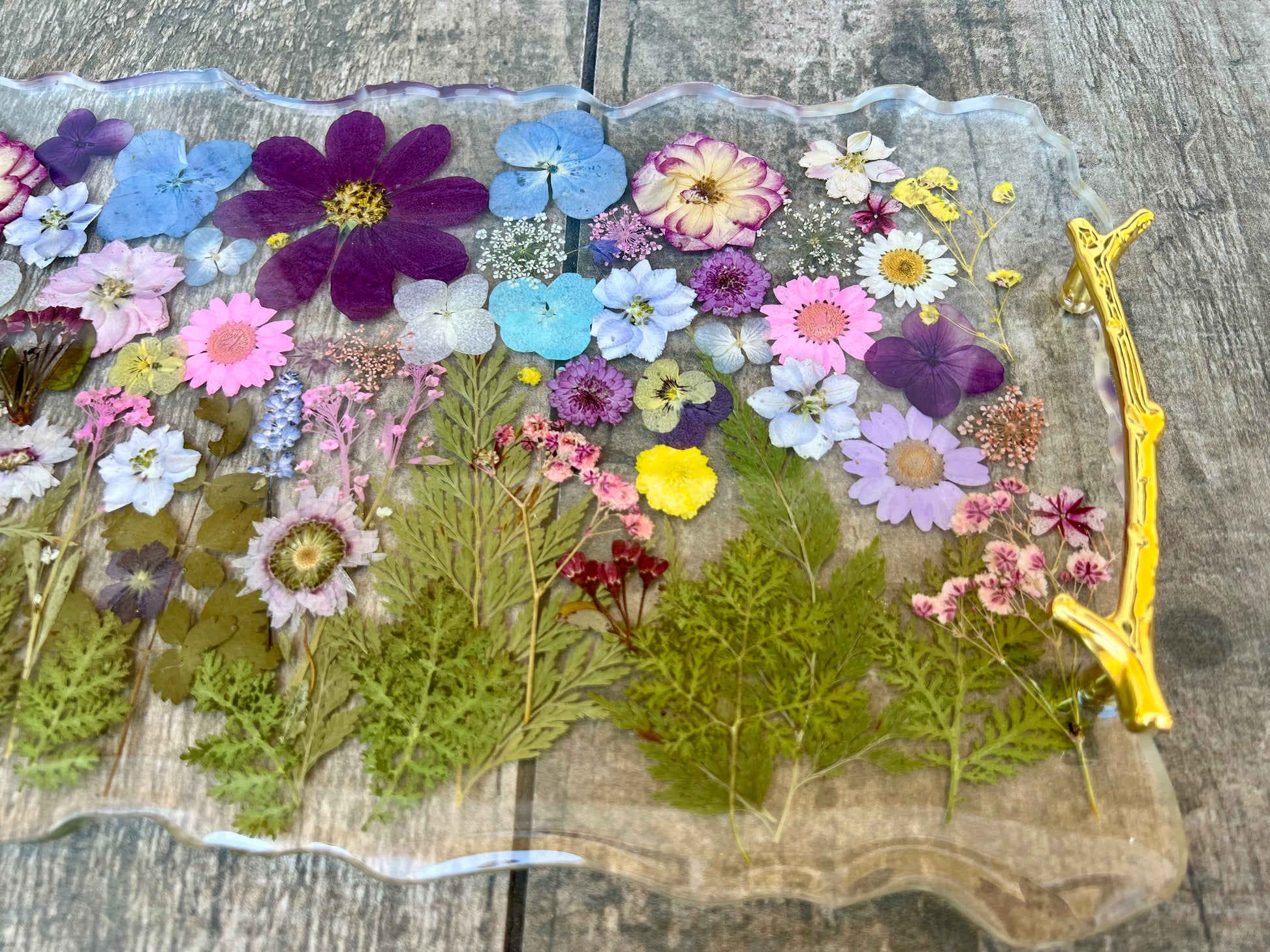 a clear glass tray with a variety of colorful flowers and leaves pressed onto it, creating a visually appealing and natural display.